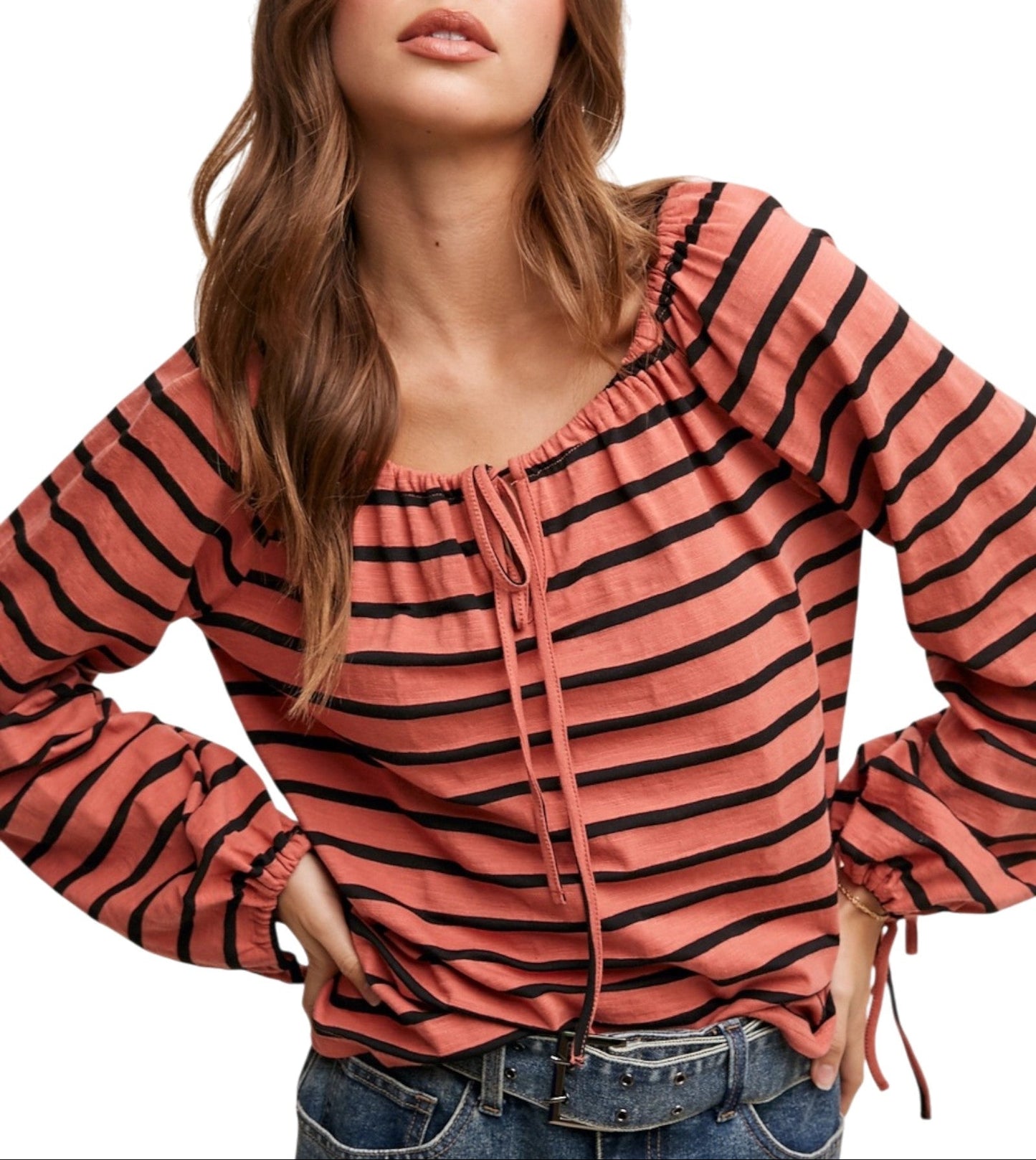Woman wearing a coral striped long-sleeve top with a white background.