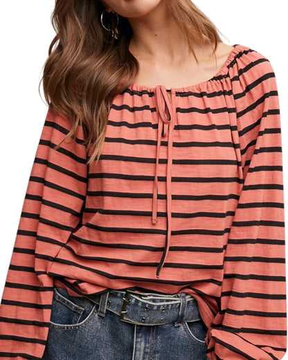 Person wearing a coral striped long-sleeve top with a white background.