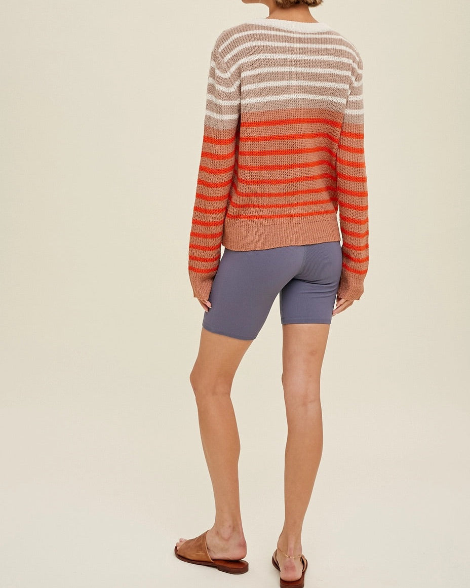 Woman wearing a striped sweater and shorts on a plain background.