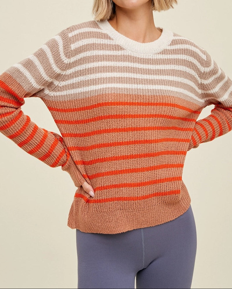 Woman wearing a striped sweater with coral and beige colors on a beige background.