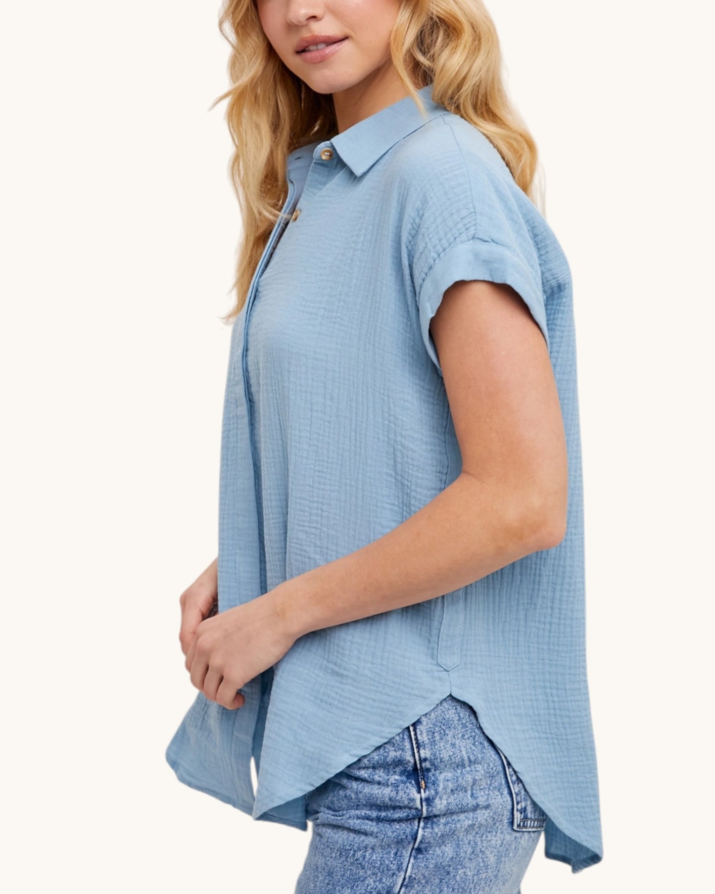 Woman wearing a light blue sleeveless checkered shirt on a white background.