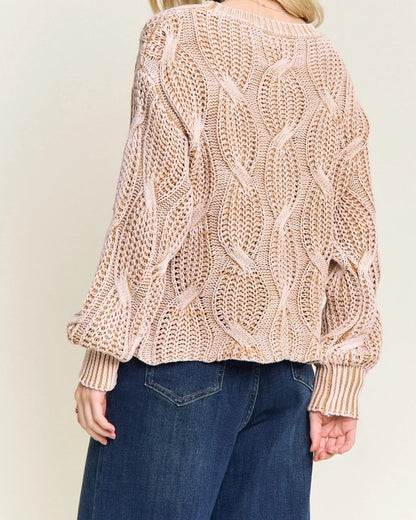 Woman wearing a beige knitted cotton sweater and blue jeans on a plain background.