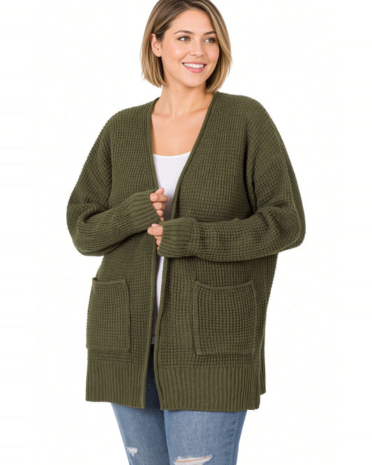 Woman wearing a dark olive waffle open cardigan with white tee shirt and blue jeans.