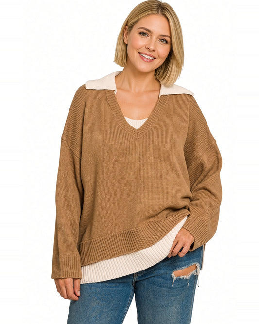 A woman wearing a deep camel/brown ribbed knit sweater with a cream-colored contrast collar and hem, paired with blue jeans, against a plain white background.