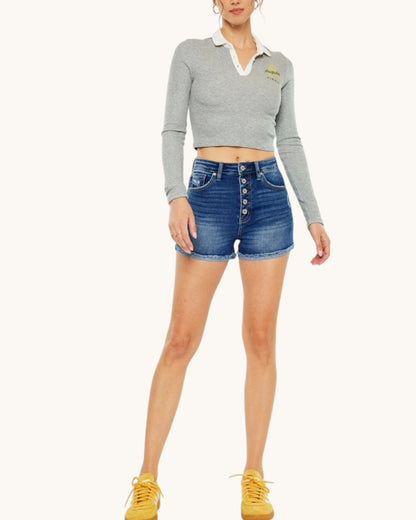 Person wearing a gray cropped sweater and blue denim shorts on a white background.