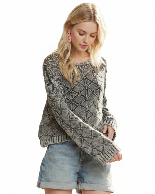 Woman wearing a charcoal diamond patterned sweater and denim shorts on a white background.