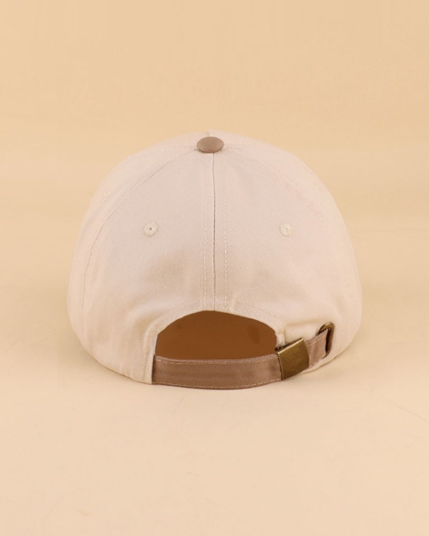 Beige cap with brown strap on a beige background.
