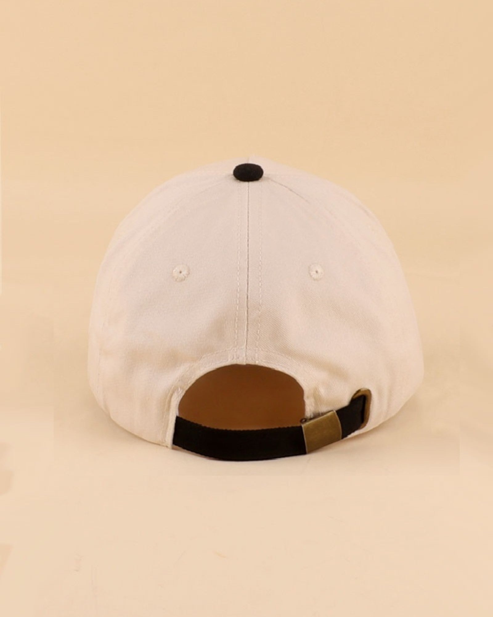 Cream and black baseball cap on a beige background.