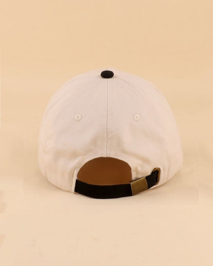 Cream and black baseball cap on a beige background.
