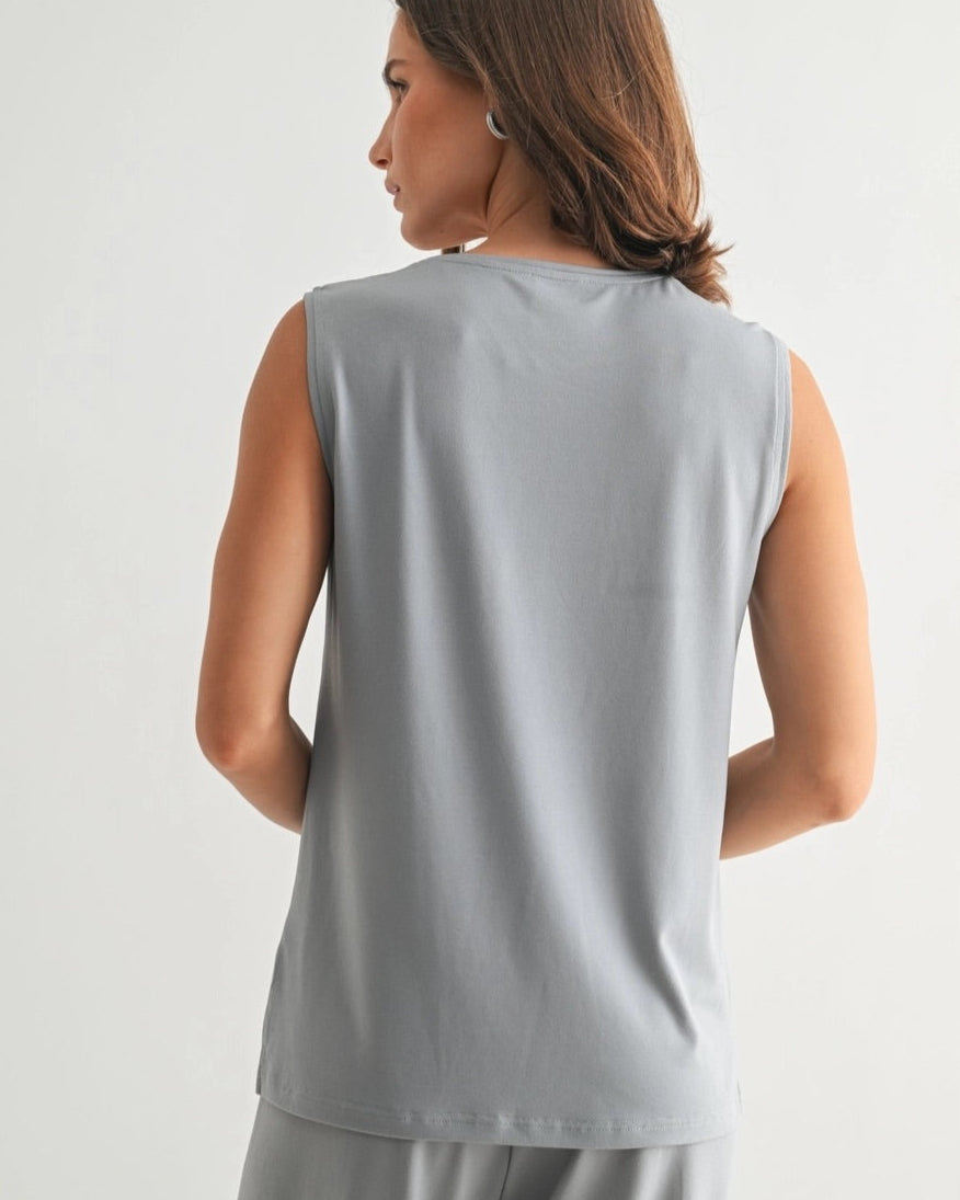 Woman wearing a dusty blue sleeveless lounge tank with relaxed drape and soft stretch.
