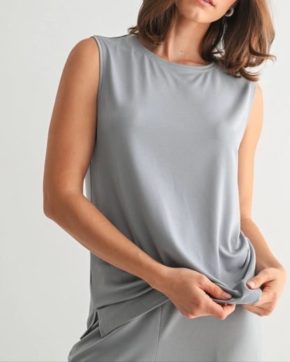Woman wearing a dusty blue sleeveless lounge tank with relaxed drape and soft stretch.