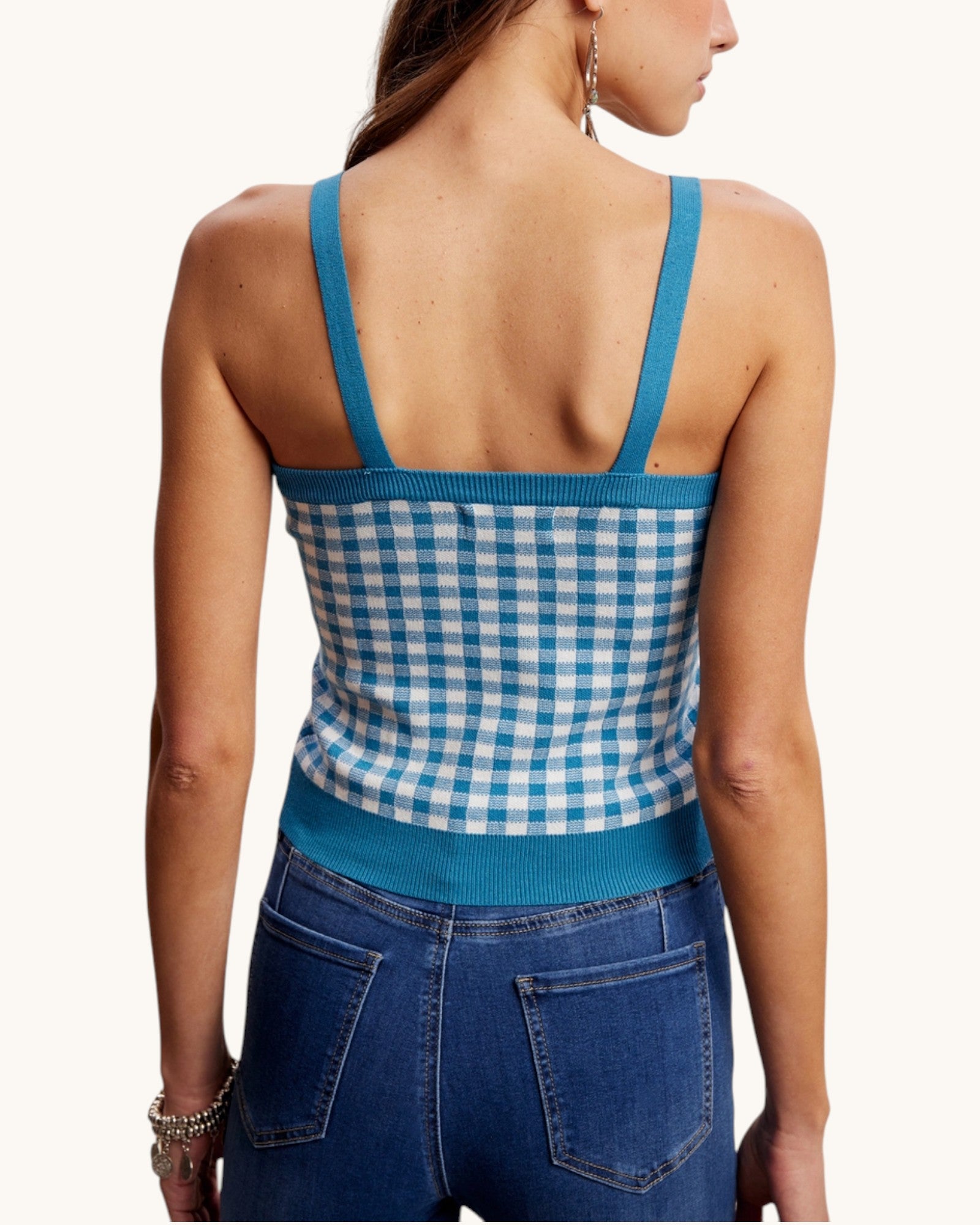 Woman wearing a blue and white checkered top with open back.