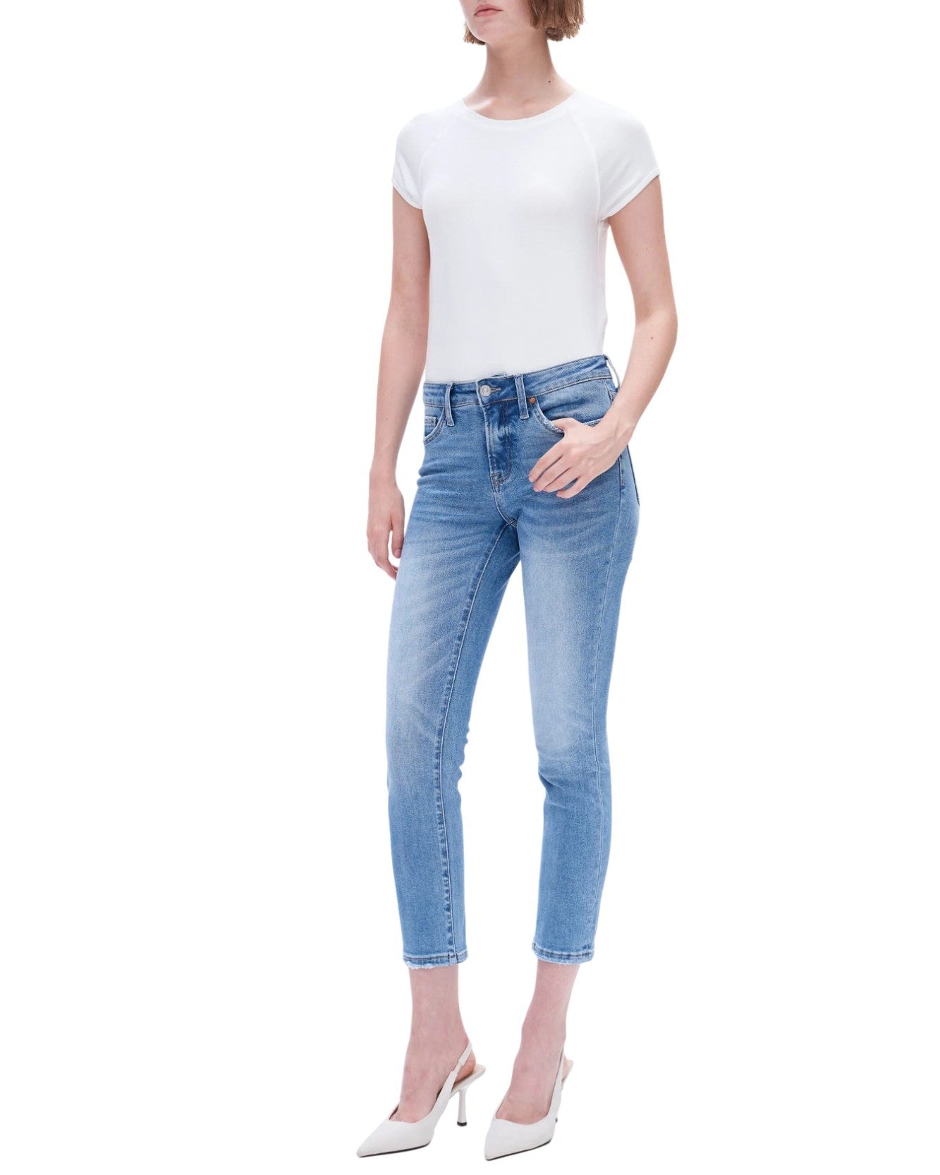 Woman wearing medium blue jeans and a white top on a white background.