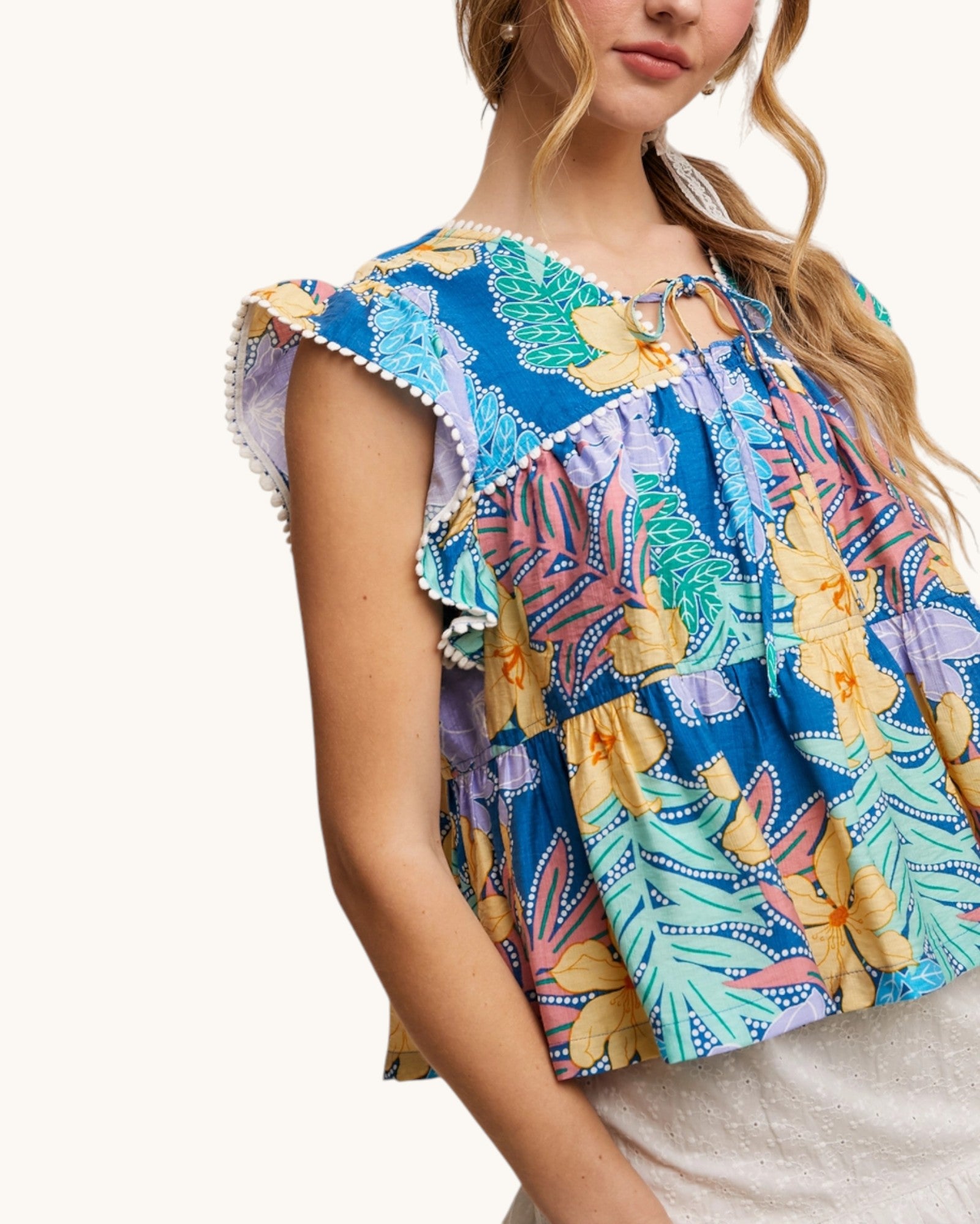 Colorful tropical print top worn by a person on a white background.