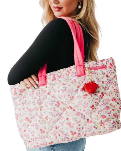 Person holding a floral tote bag with pink handles on a white background.