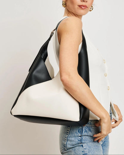 Woman holding a black and white handbag against a plain background