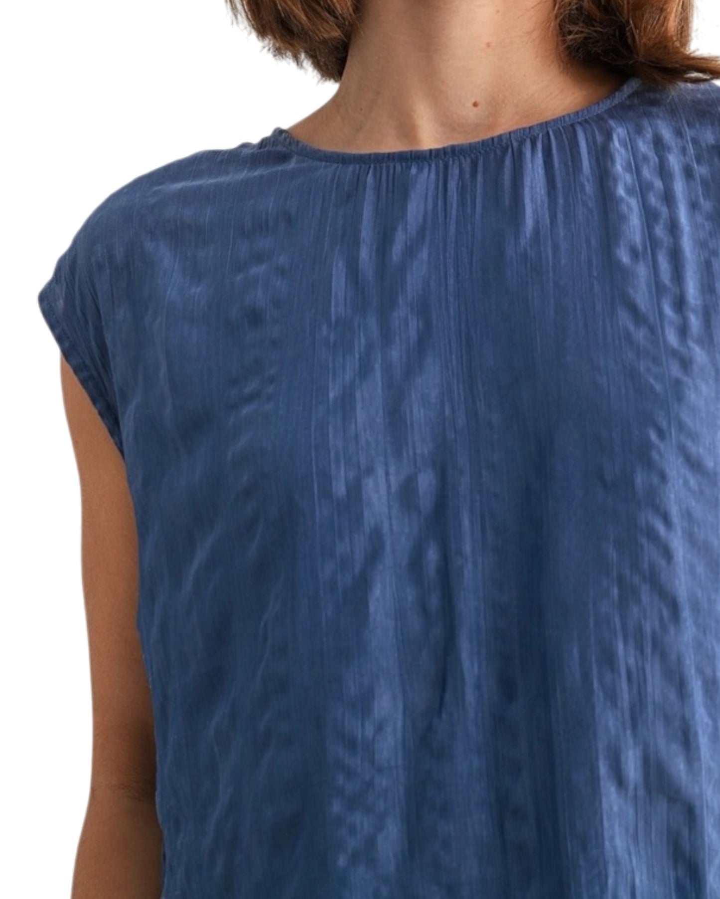 Woman wearing a blue textured sleeveless top on a white background.