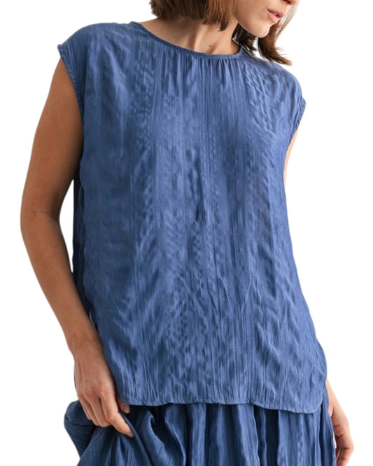 Woman wearing a blue textured sleeveless top on a white background.