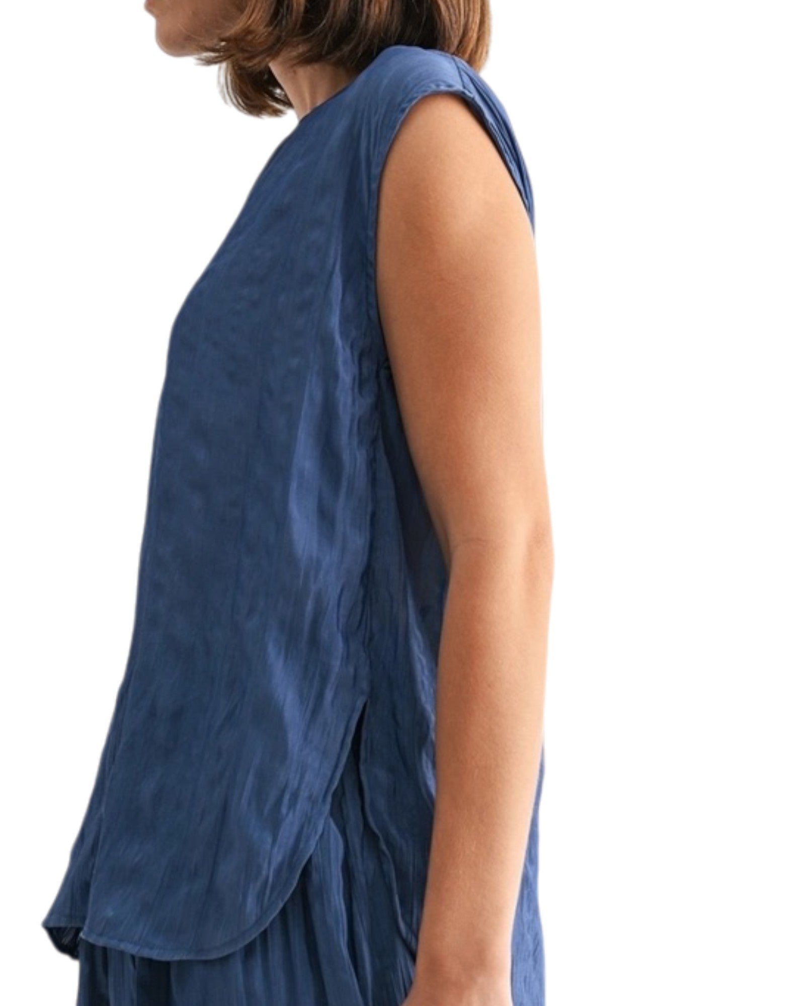 Woman wearing a blue textured sleeveless top on a white background.