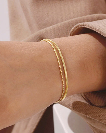 Gold bracelet on a person's wrist with a neutral background