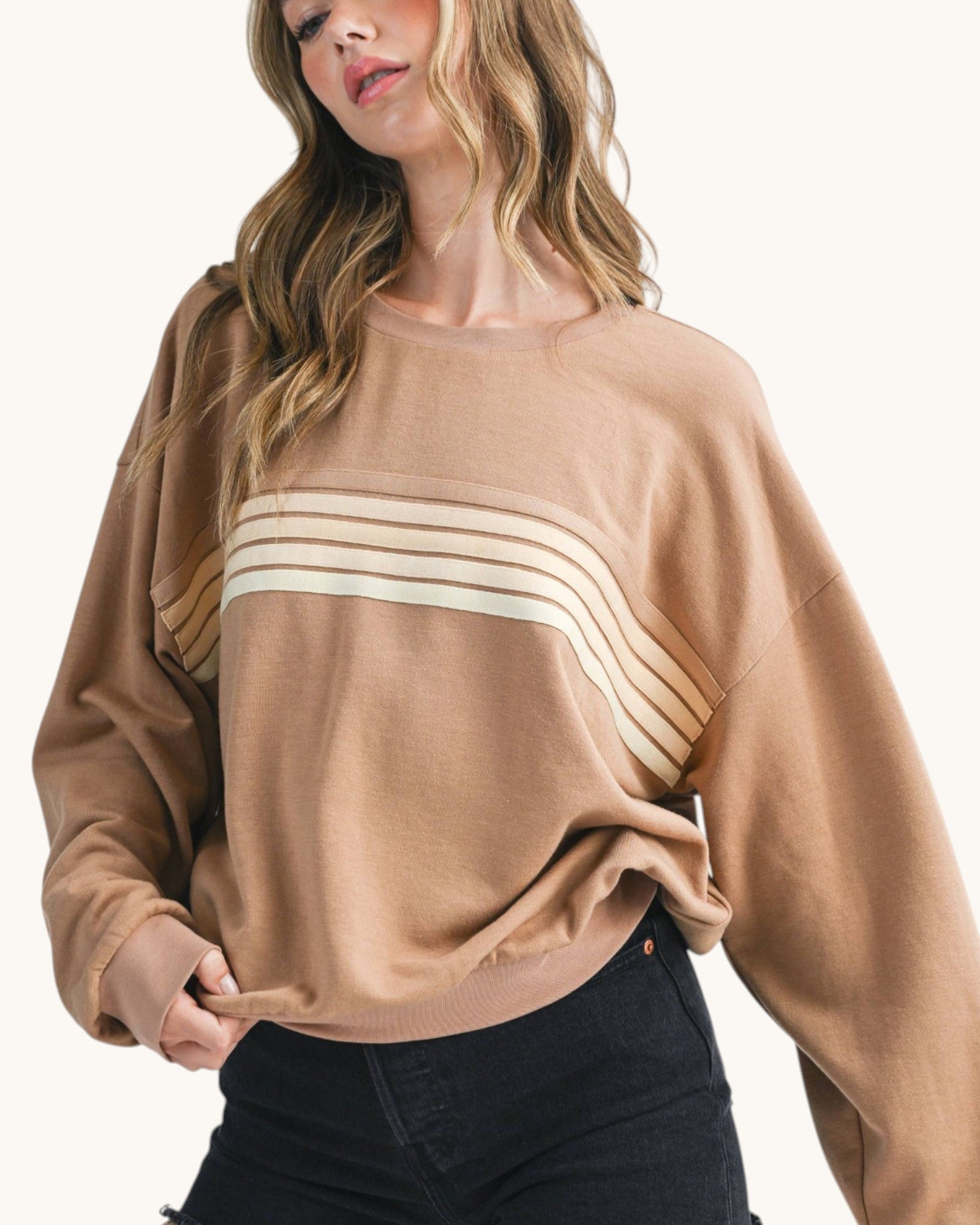 Woman wearing a brown sweatshirt with tonal retro stripes. 