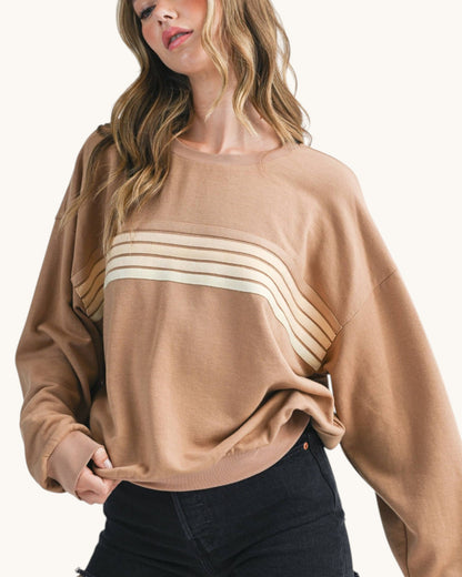 Woman wearing a brown sweatshirt with tonal retro stripes. 