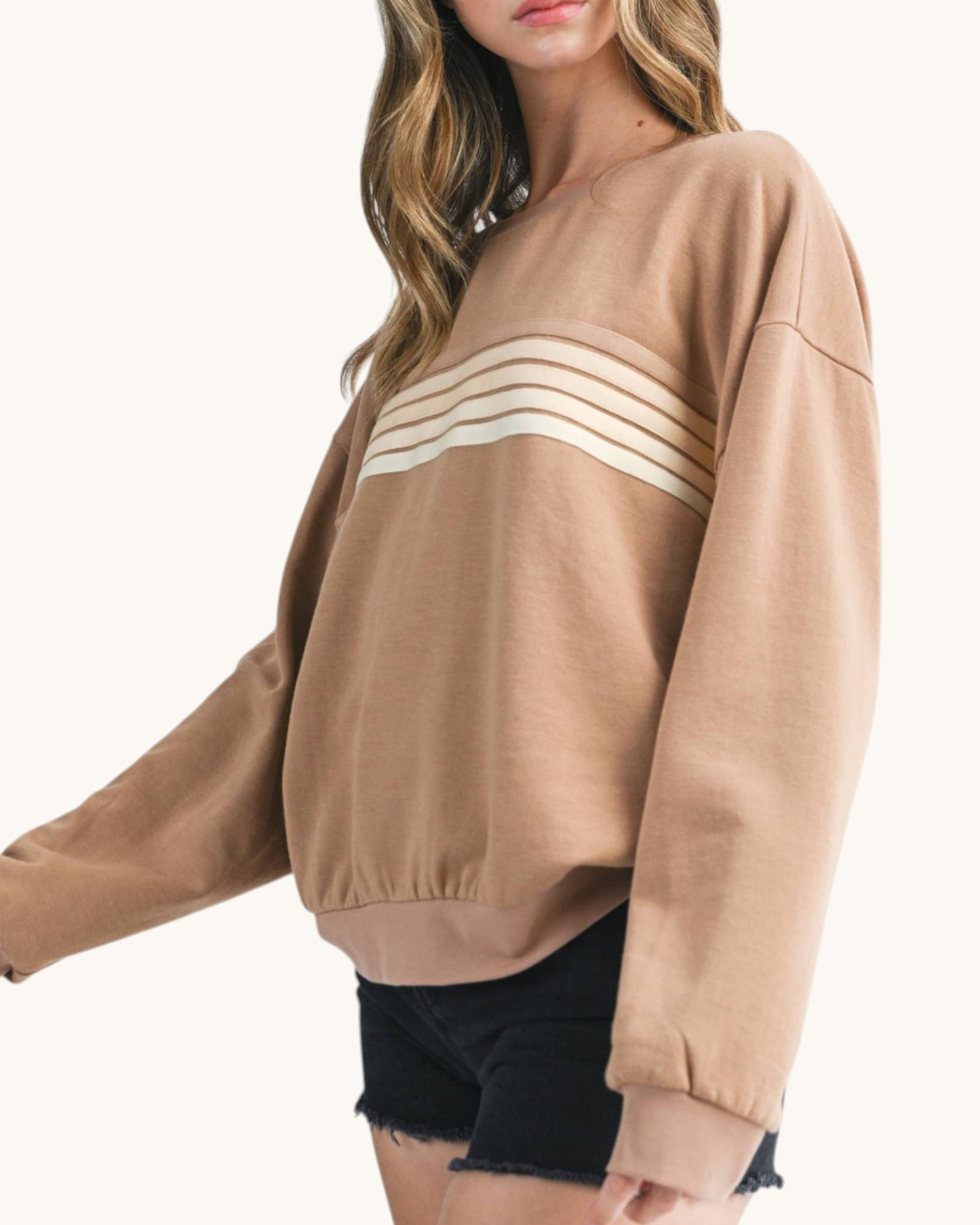 Woman wearing a brown sweatshirt with tonal retro stripes. 
