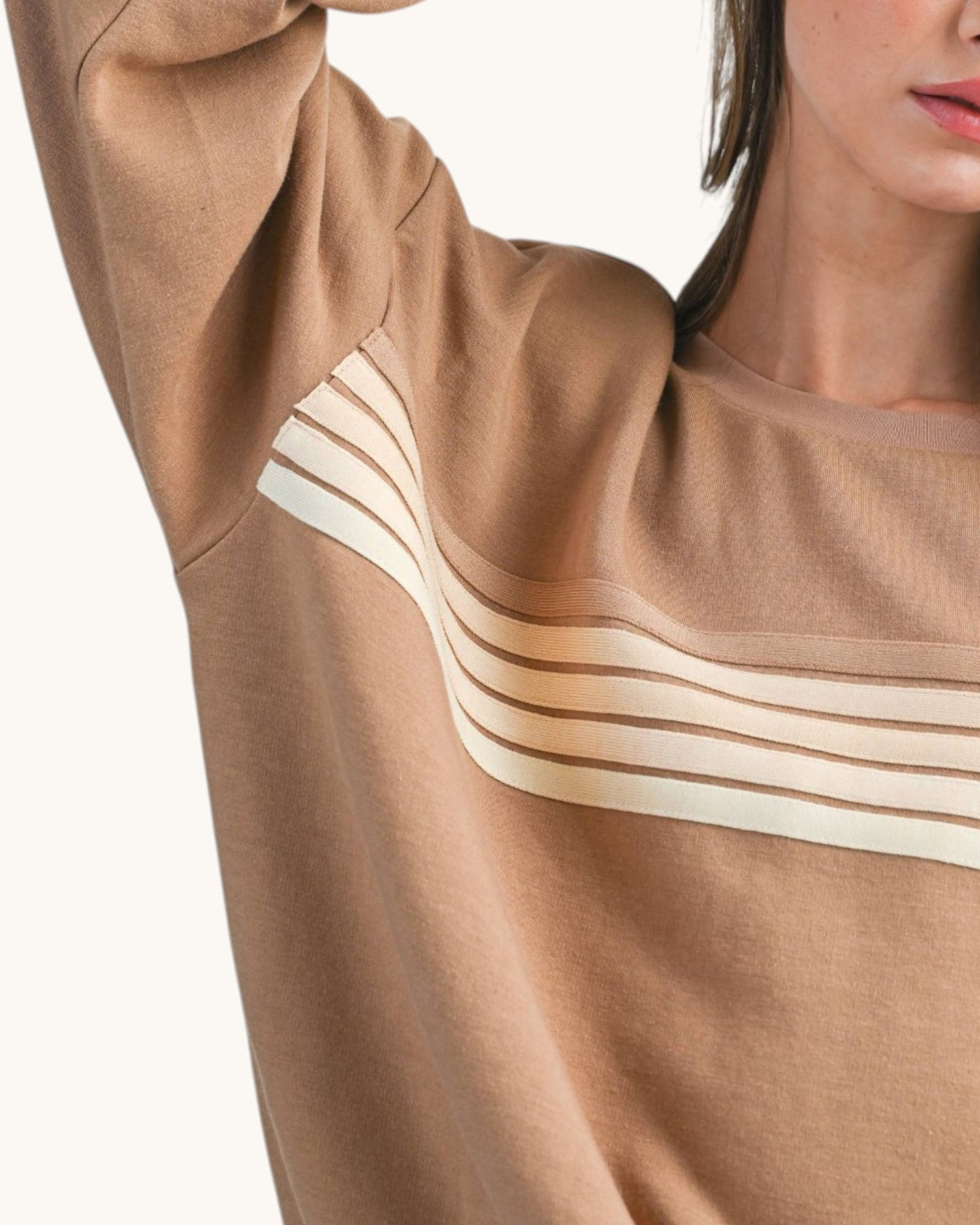Close up view of a woman wearing a brown sweatshirt with tonal retro stripes. 