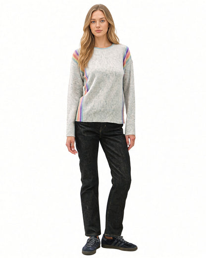 Full-length front view of model wearing grey Rainbow Prism crewneck sweater with rainbow stripes along the shoulders and sides.

