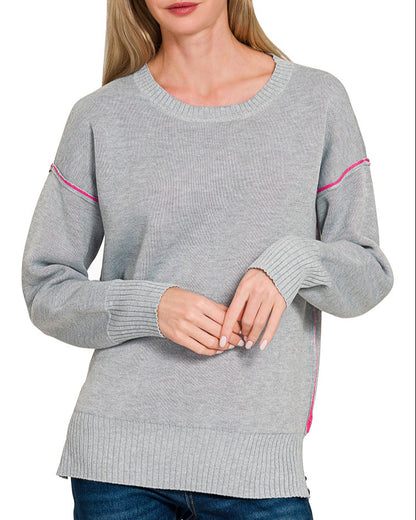 Woman wearing a gray sweater with pink contrast on a white background.