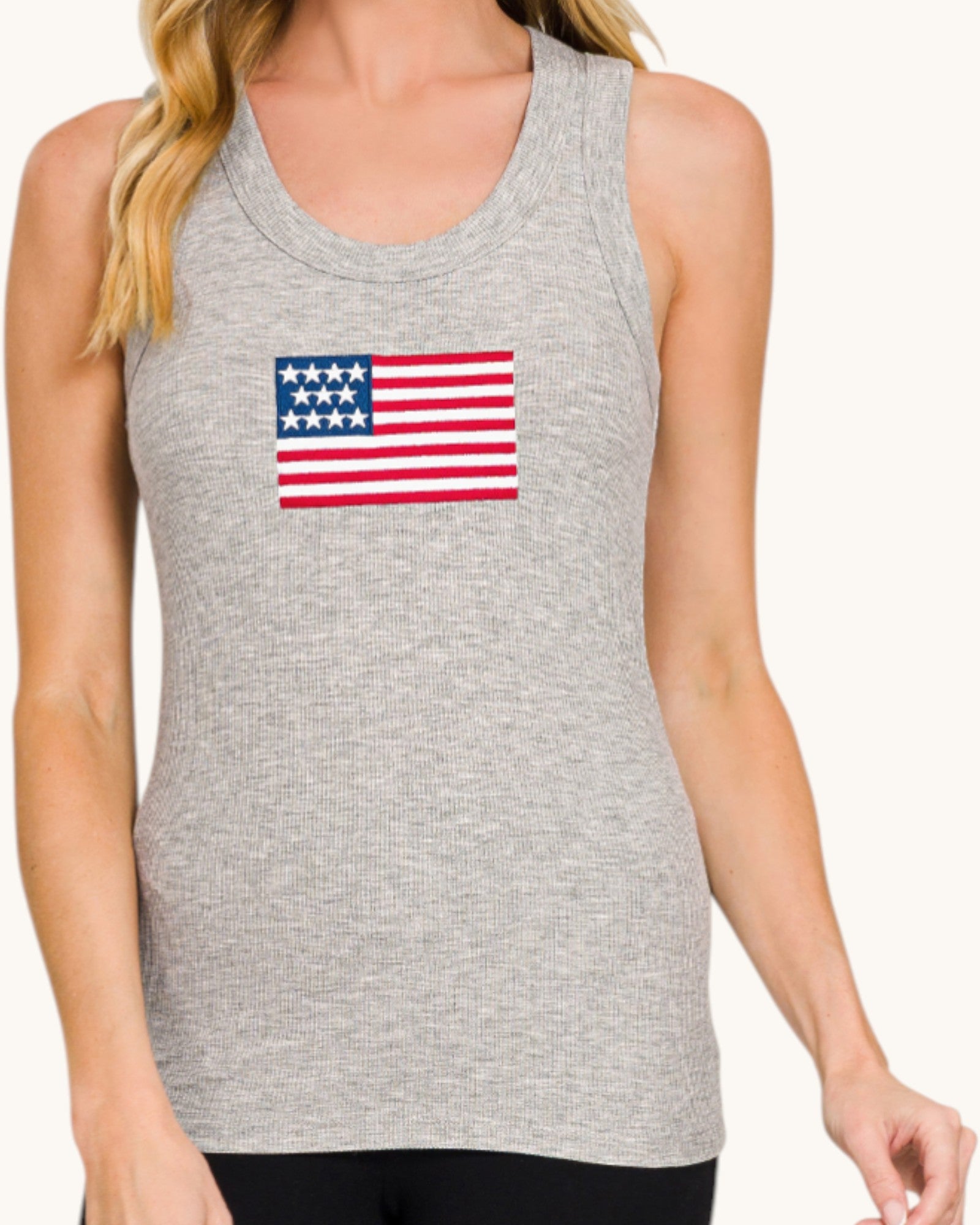 Gray tank top with American flag design worn by a person on a white background.