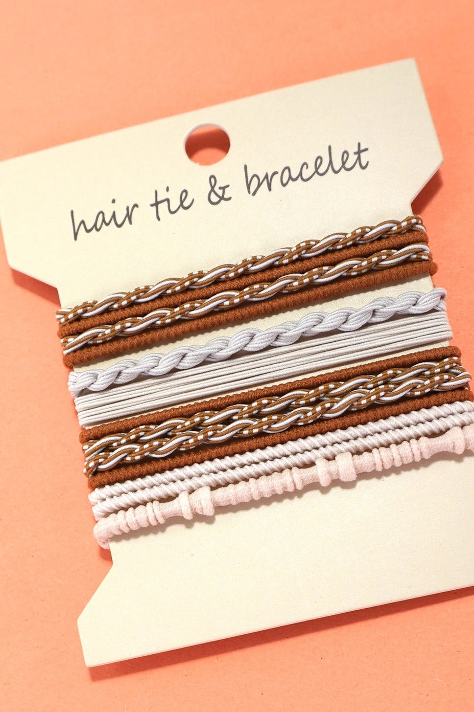Set of hair ties and bracelets on a display card with a pink background