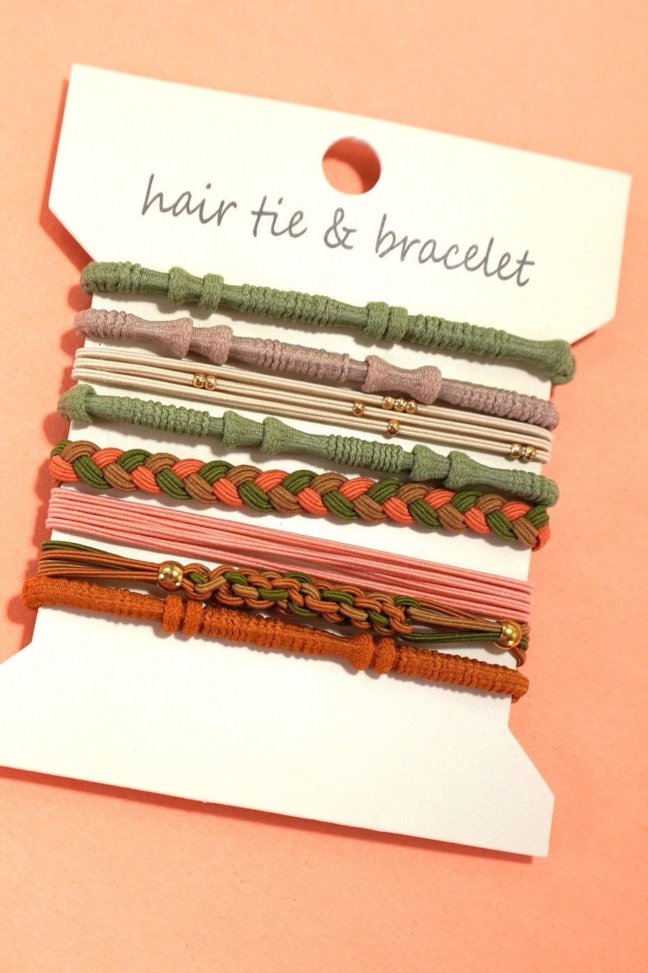 Set of hair ties and bracelets on a pink background with a label