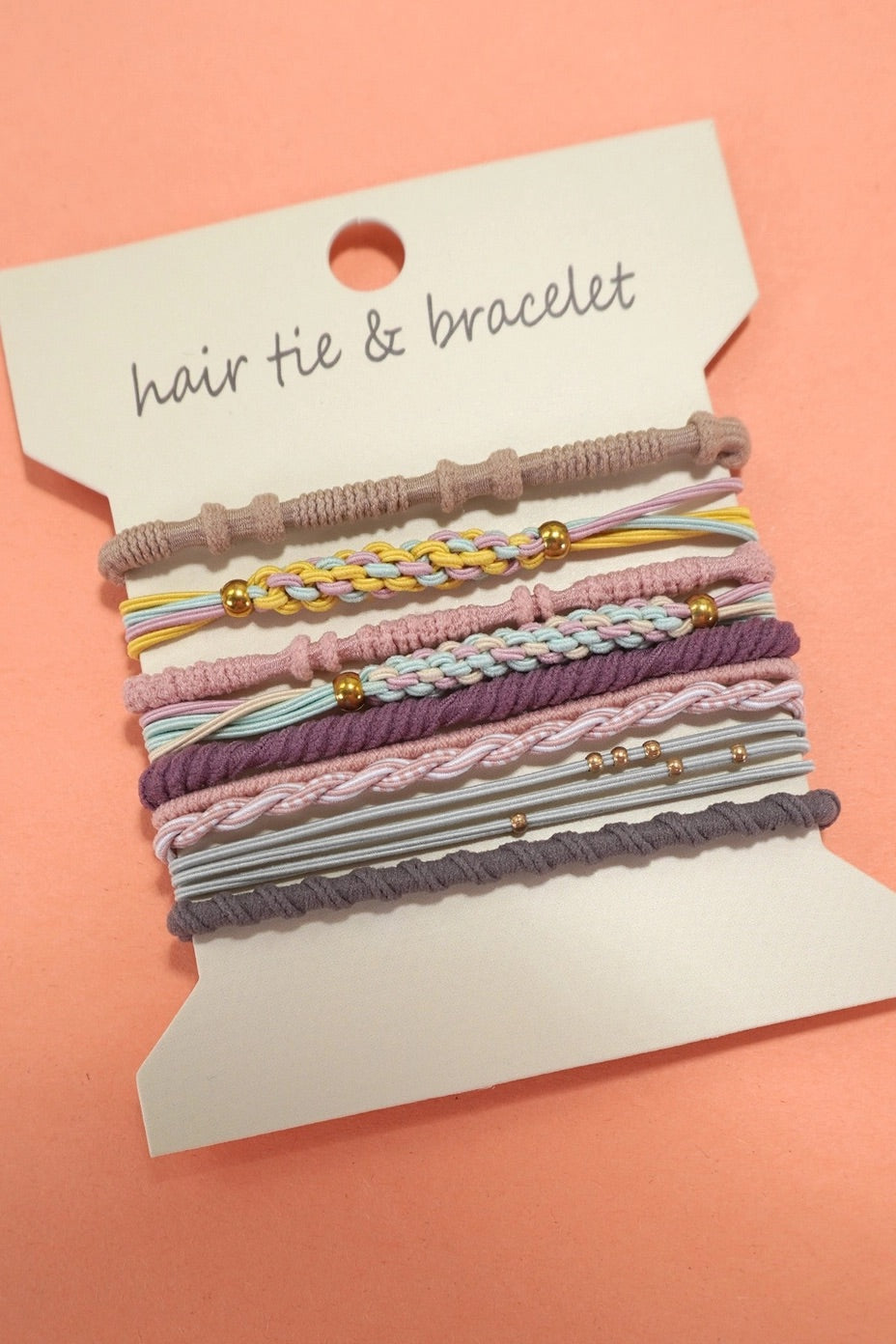 Set of hair ties and bracelets on a display card with a pink background