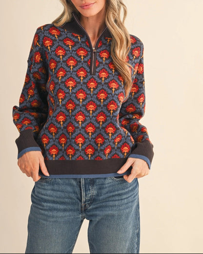 Patterned floral 1/2 zip brown and blue sweater with red and orange vintage floral accents on a white background.