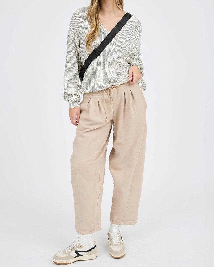 Woman wearing a striped sweater and beige pants on a white background.
