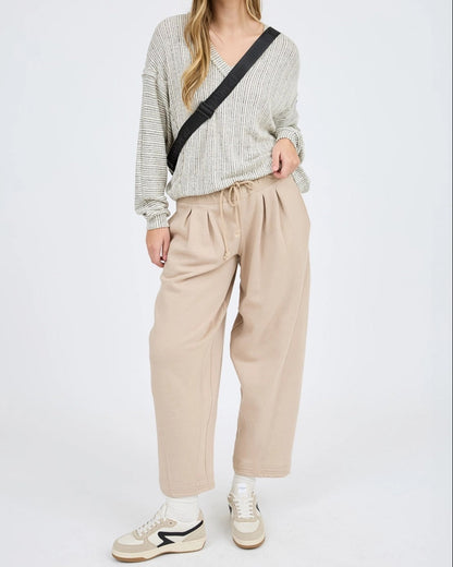 Woman wearing a striped sweater and beige pants on a white background.