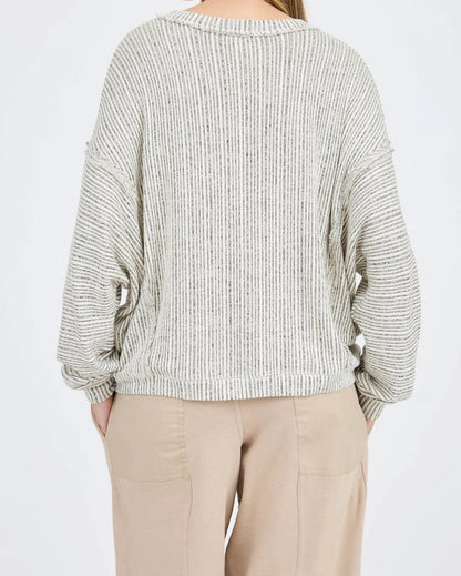Woman wearing a textured sweater and beige pants on a white background