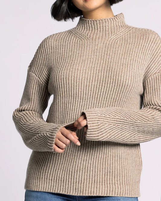 Person wearing a beige ribbed sweater on a light gray background.