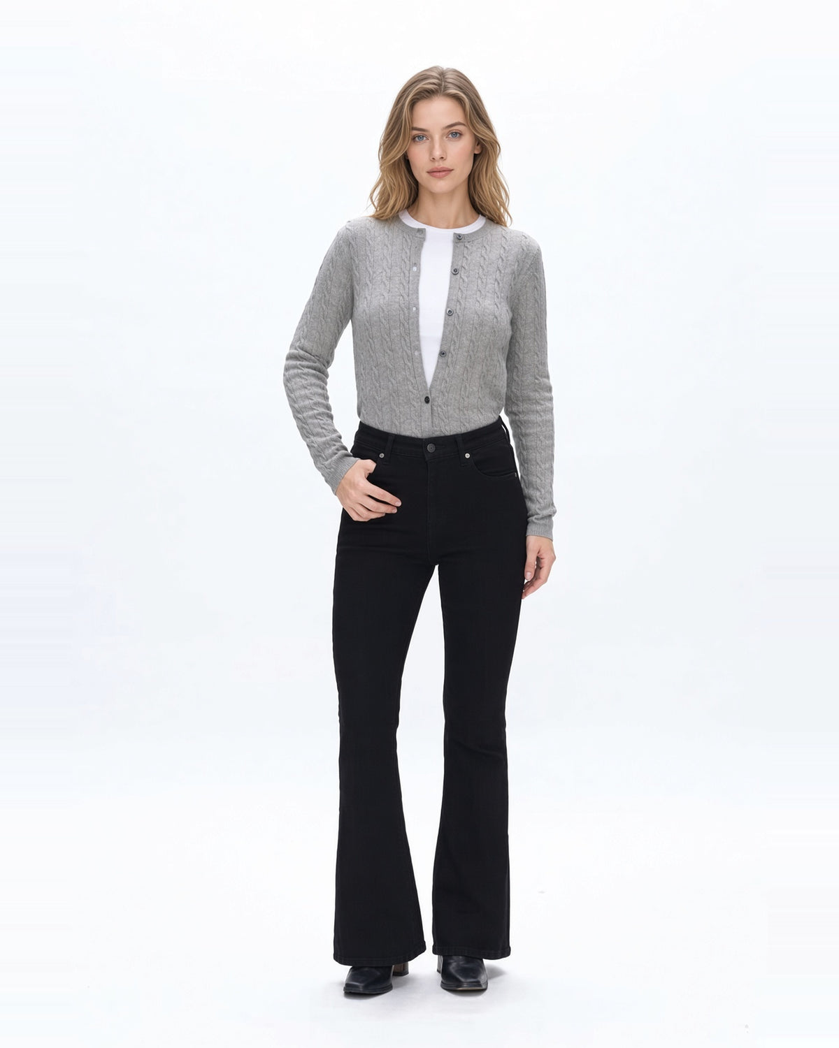 Woman wearing high rise flare denim black jeans with gray sweater and fitted white tee shirt and black boots.
