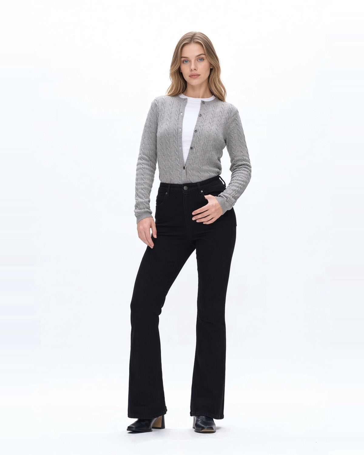 Woman wearing high rise flare denim black jeans with gray sweater and fitted white tee shirt and black boots.