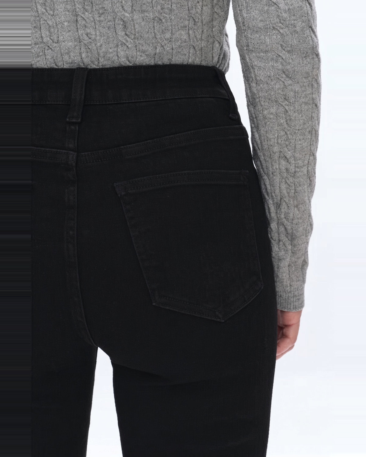 Back view of waist to thigh of high rise black denim flare jeans.