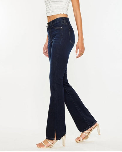 Woman wearing Kan Can Dark Wash High Rise Bootcut Jeans with side slit detail.