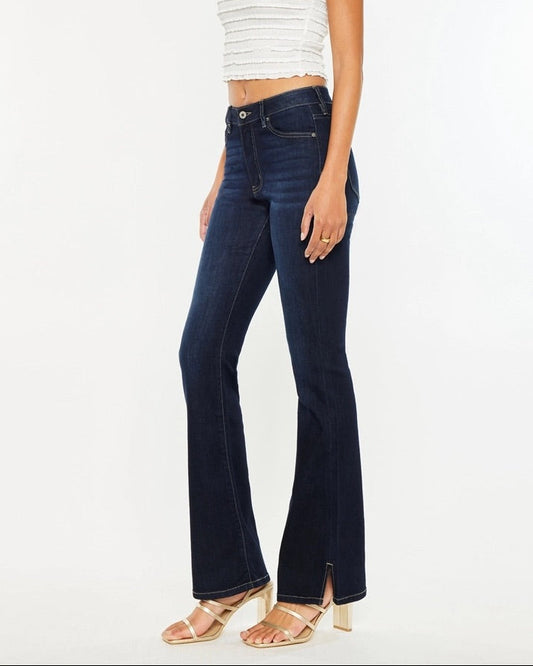 Woman wearing Kan Can Dark Wash High Rise Bootcut Jeans with side slit detail.