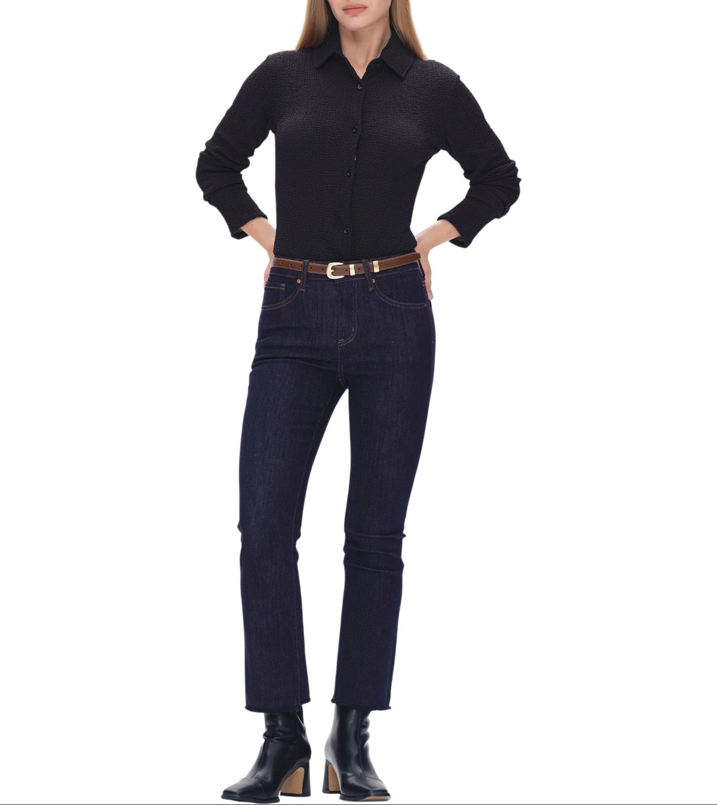 Woman wearing a black shirt and dark blue jeans on a white background.