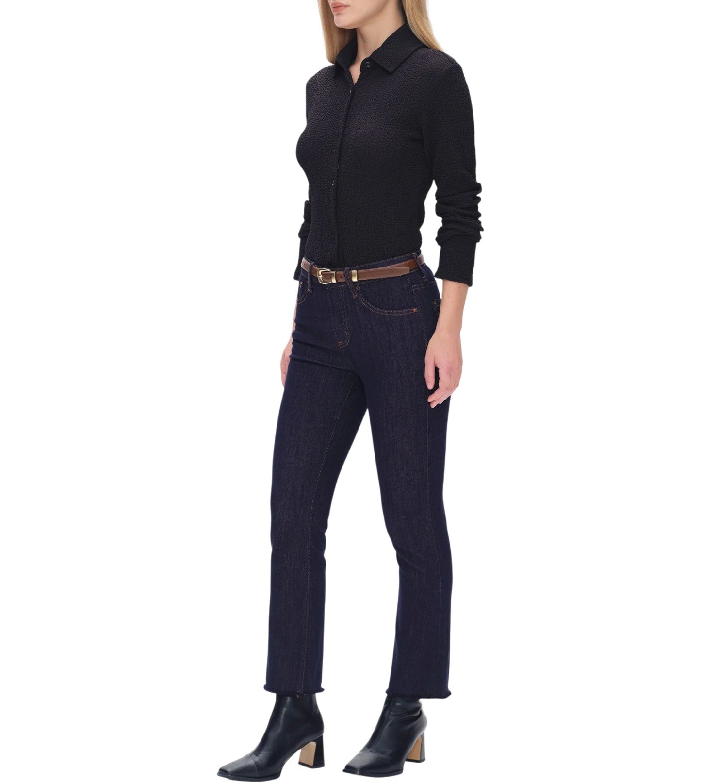 Woman wearing a black shirt and dark jeans on a white background