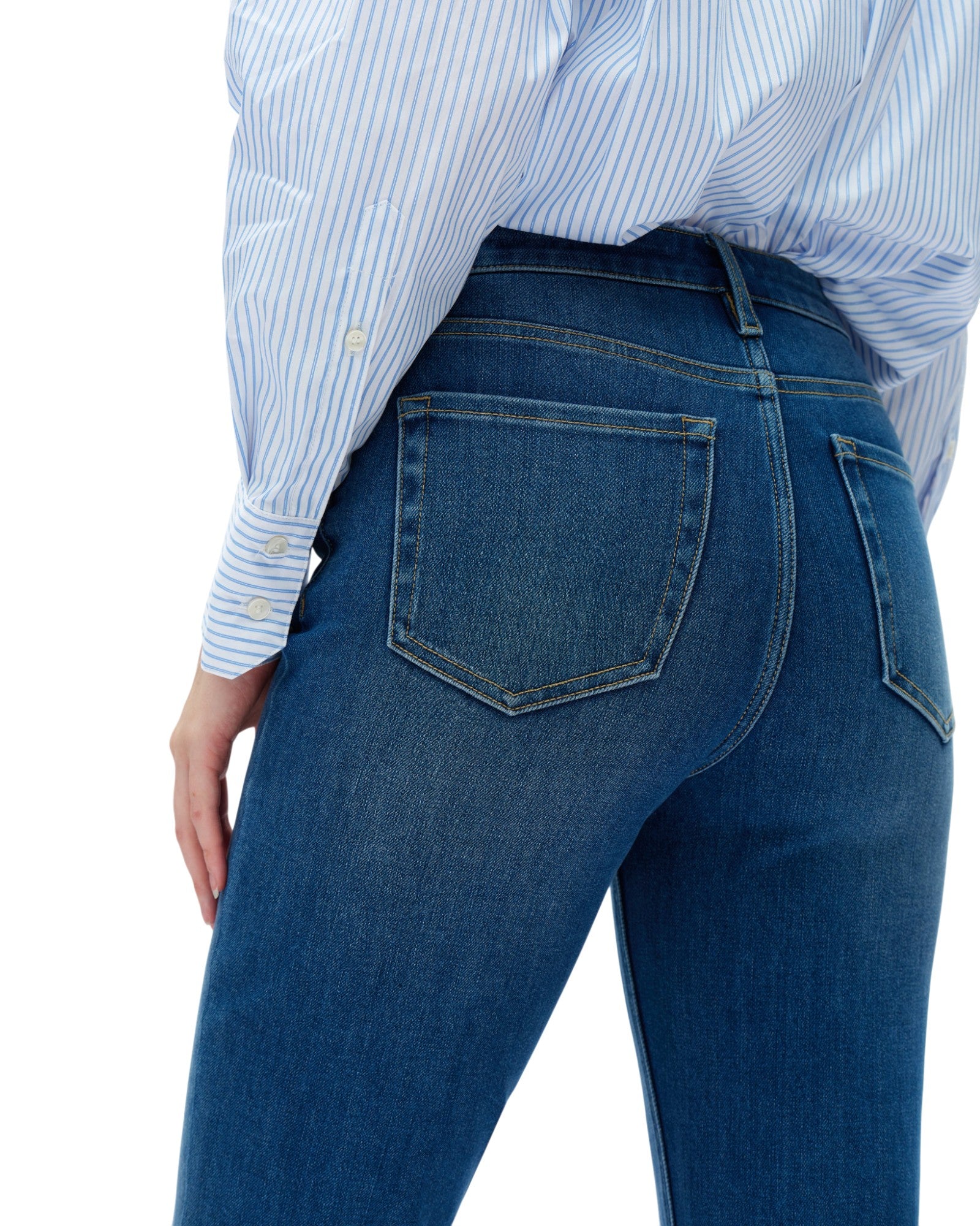Person wearing blue jeans and a striped shirt on a white background. 