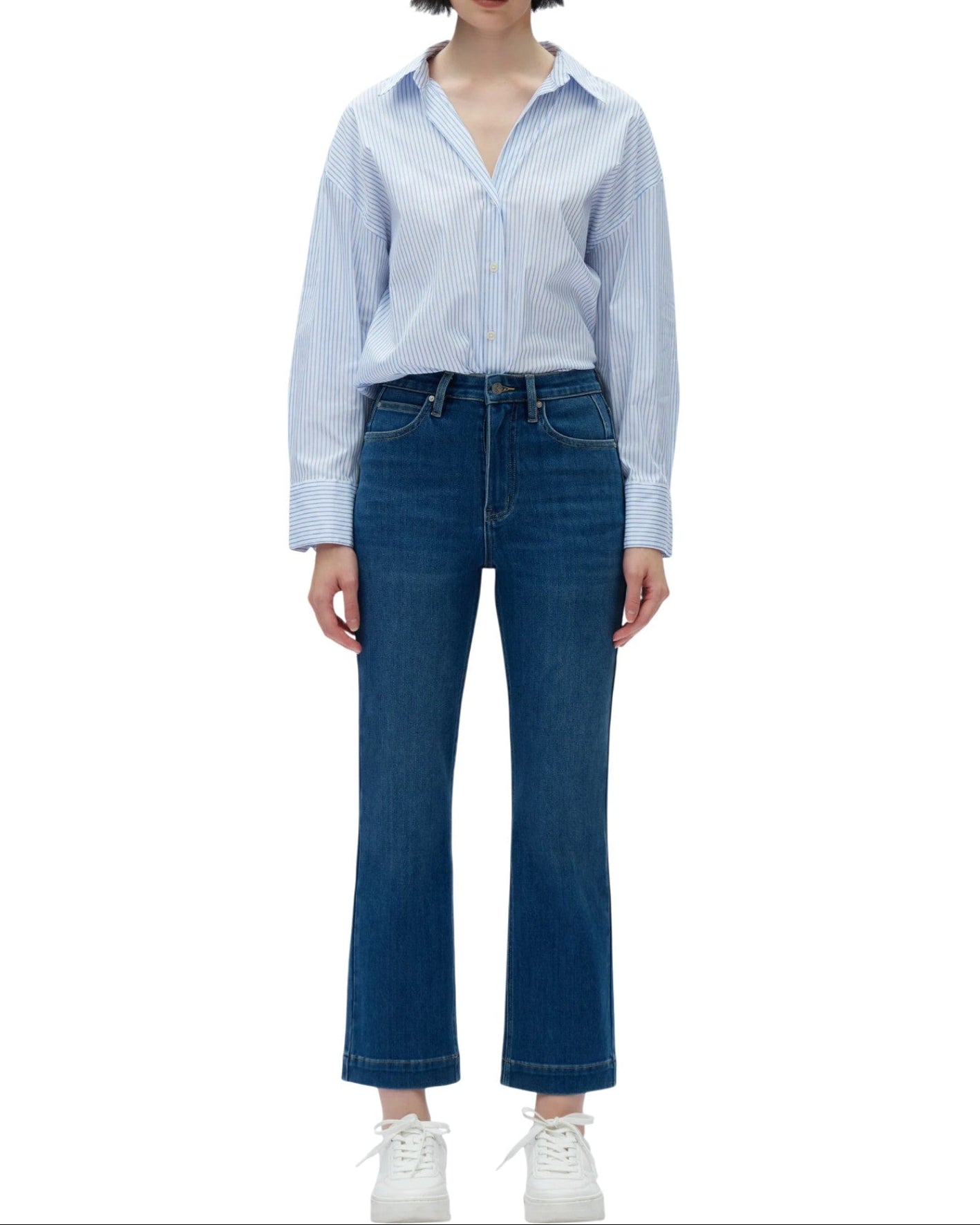 Person wearing a light blue button-up shirt and dark blue jeans on a white background.