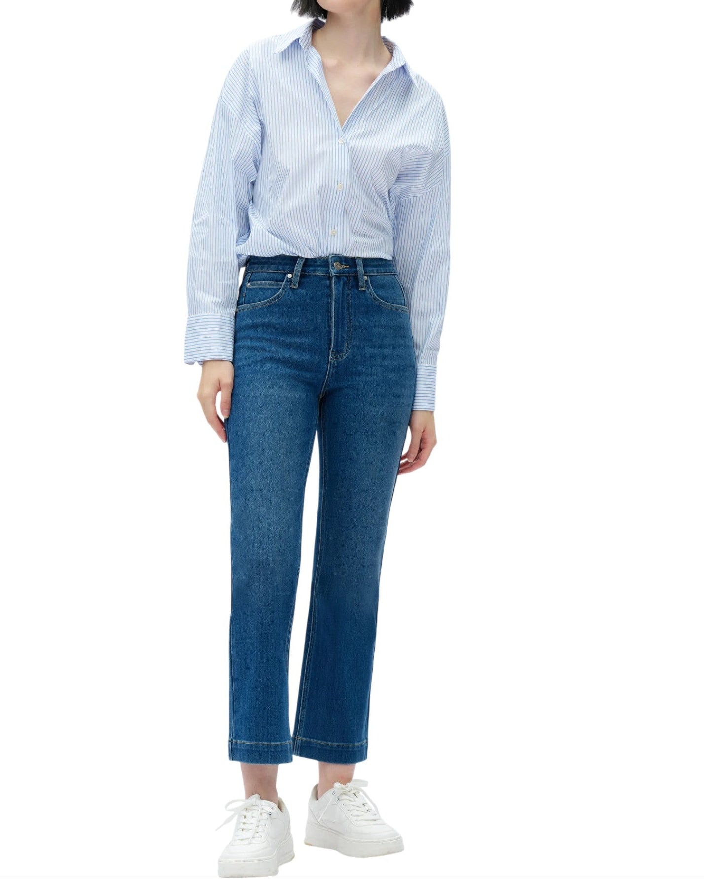 Woman wearing a light blue striped shirt and dark blue jeans on a white background.