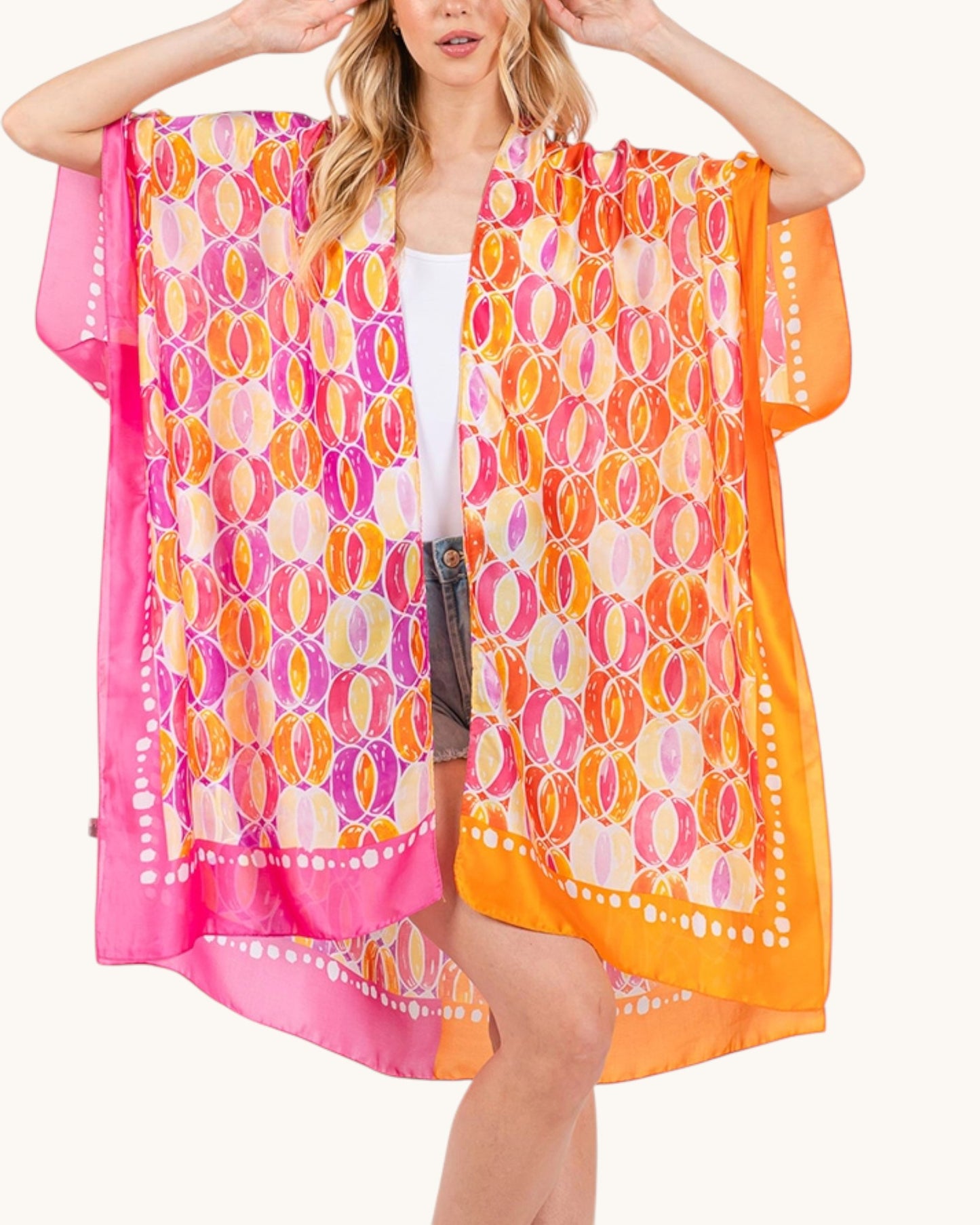 Woman wearing a colorful pink and orange patterned cover-up on a white background.
